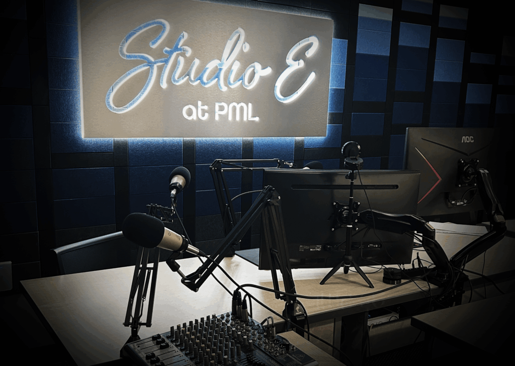 Studio E E sign lit up behind av recording equipment and computers